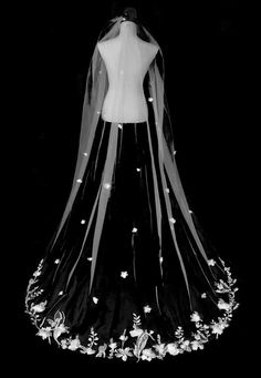 a black and white photo of a wedding dress with flowers on the skirt is shown in front of a mannequin's head