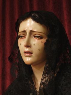 a mannequin wearing a black lace veil with blood on it's face