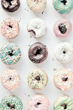 there are many different donuts on the white table top, and one has sprinkles all over it