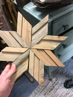 a person holding up a wooden snowflake on top of a table next to a dresser