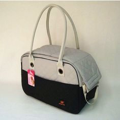 a black and white handbag on a white surface with a tag hanging from the handle