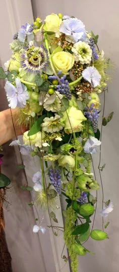 a bouquet of flowers is being held up by someone's hand in front of a door