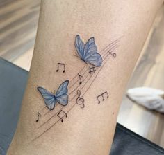 two blue butterflies with musical notes on their wings are shown in this tattoo by the artist