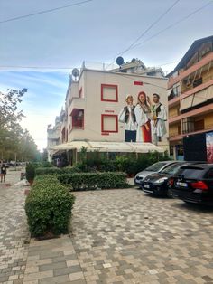 a large mural on the side of a building next to cars parked in front of it