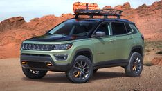 a green jeep parked in the desert with its roof rack on it's top