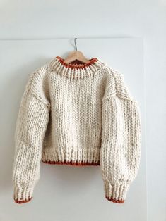 a white sweater hanging on a wooden hanger