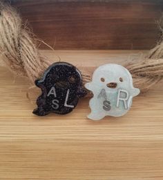 two small ghost decorations sitting on top of a wooden table next to twine of twine