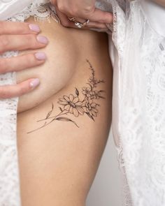 a woman's breast is shown with flowers tattooed on the side and behind her