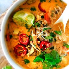 a white bowl filled with soup on top of a wooden cutting board and garnished with cilantro