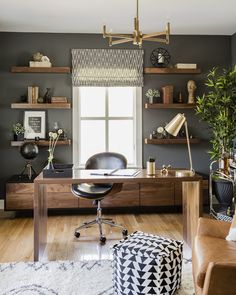 a home office with black walls and wooden desk, leather chair, potted plant on the far wall