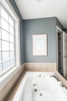 a bath tub sitting under a window in a bathroom