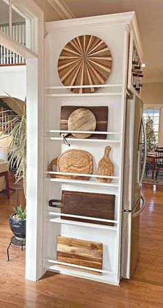 a white book shelf with wooden cutting boards on it