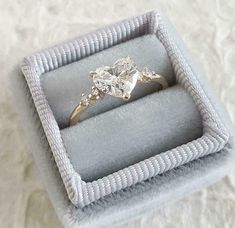 an engagement ring in a box on top of a white cloth covered surface with a diamond center