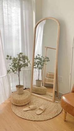 a large mirror sitting on top of a wooden floor next to a chair and potted plant