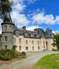 an old castle like building with turrets and windows on the top floor, surrounded by greenery