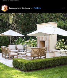 an outdoor dining area with chairs and umbrellas in the grass next to some bushes