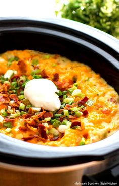 a crock pot filled with bacon, cheese and sour cream on top of it