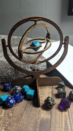 several different colored dice sitting on top of a wooden table next to an open book