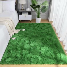 a green area rug in a bedroom with white curtains and a plant on the floor