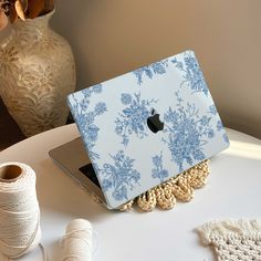 an apple laptop sitting on top of a table next to yarn and spools