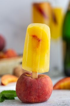 a popsicle made out of fruit sitting on top of a table next to bottles