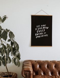 a brown leather couch sitting next to a potted plant