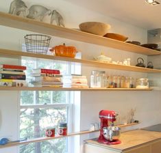 a kitchen with shelves filled with various items and bowls on top of the countertop