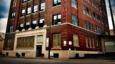 an old red brick building with windows on the top and bottom floor, in front of a cloudy sky