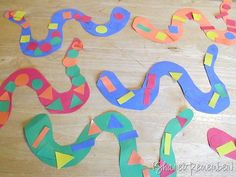 colorful paper snakes are laid out on a wooden surface with one snake in the middle