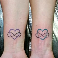 two people with matching tattoos on their wrists holding each other's hands in the shape of hearts