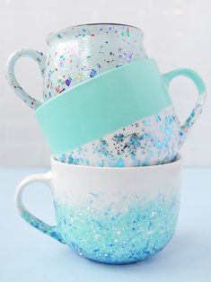 three coffee mugs stacked on top of each other with blue and white sprinkles