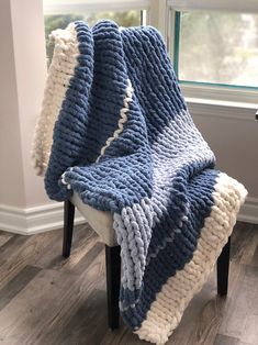 a blue and white blanket sitting on top of a wooden chair next to a window