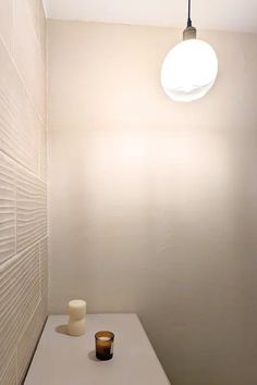 a small white table with a candle on it in a room next to a light fixture