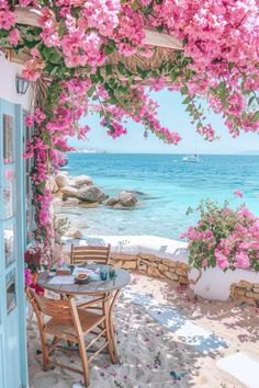 an outdoor dining area with pink flowers on the beach