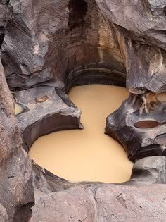 there is a hole in the rocks that has water coming out of it and some dirt on the ground