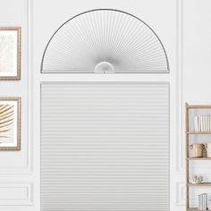 a living room with white walls and an arched window covered in cellular shades on the windowsill