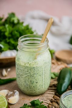 a jar filled with pesto sauce next to sliced limes and cilantro