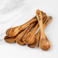 four wooden spoons with names on them sitting next to each other in front of a marble counter top