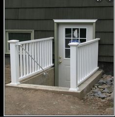 a small white door is open on the side of a house with rocks in front of it