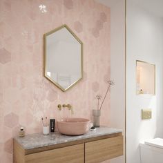 a bathroom with pink hexagonal tiles and gold accents on the wall, along with a sink