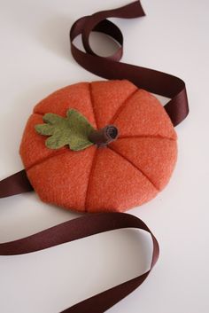 a small orange pumpkin sitting on top of a brown ribbon