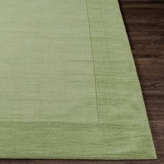 a green rug on top of a wooden floor