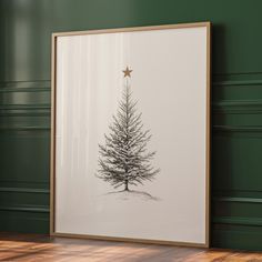 a christmas tree with a star hanging from it's side in a frame on the floor