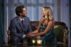 a man and woman sitting on a couch in front of a table with two candles