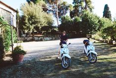 two motorbikes parked next to each other in front of some trees and bushes