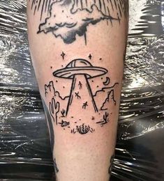 a tattoo on the leg of a man with an alien ship flying over it and stars