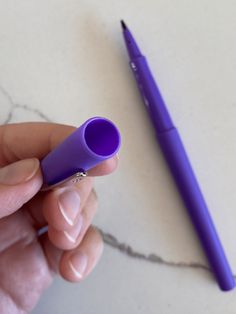 a person holding a purple pen in their left hand