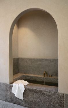 a bath room with a sink and a towel on the ledge next to an archway