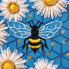 a close up of a bee on a blue background with white daisies and honeybees