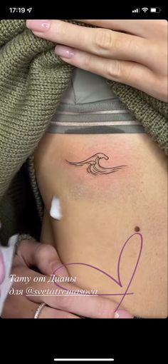 a woman's stomach with a small wave tattoo on the side of her belly